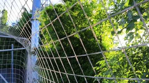 Sunbeams filter through the goal net of a nearby football field. Handheld video Stock Footage 337544845