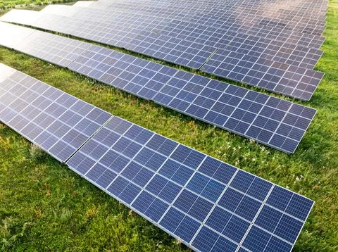 Sunbeams hitting blue solar panels in a field, drone view. Stock Photos