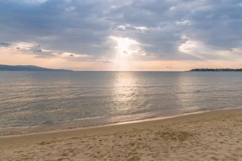 Sunbeams or sun rays peeking through the clouds at a sunrise on beautiful bea Stock Photos