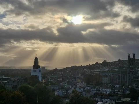 Sunbeams over city skyline at dramatic sunset Stock Photos