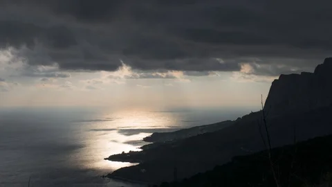 Sunbeams over glittering sea surface near rocky coasts at twilight, time lapse Stock Footage 125451463