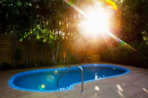 Sunbeams over swimming pool in backyard Stock Photos