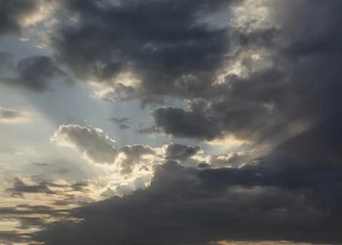 Sunbeams piercing the clouds at dawn. Stock Photos
