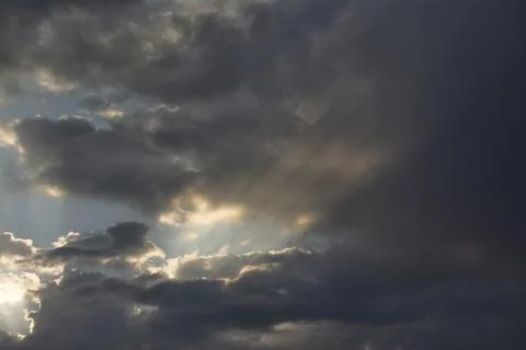 Sunbeams piercing the clouds at dawn. Stock Photos