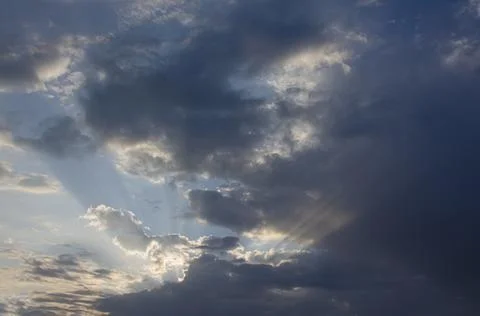 Sunbeams piercing the clouds at dawn. Stock Photos