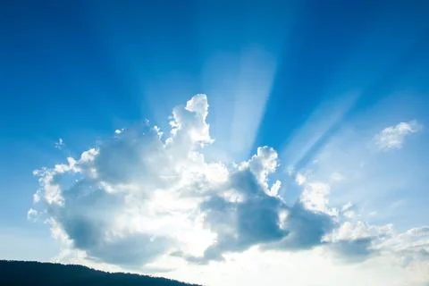 Sunbeams shines through the cloud over a mountain. Stock Photos