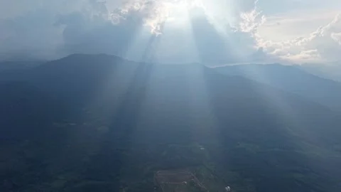 Sunbeams slice through clouds over mountain ranges Video stock 339842690