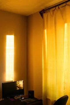 Sunbeams at sunset fall on computer desk in apartment. Stock Photos