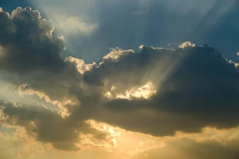 Sunbeams through the clouds at sunset Stock Photos