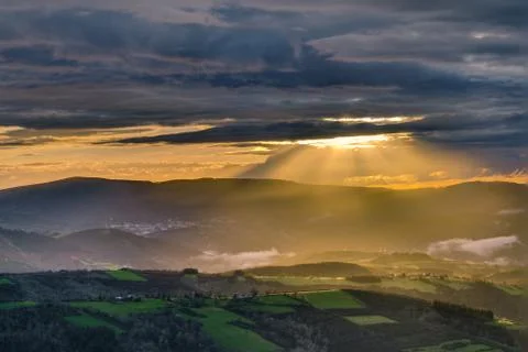 Sunbeams through the clouds at sunset Stock Photos