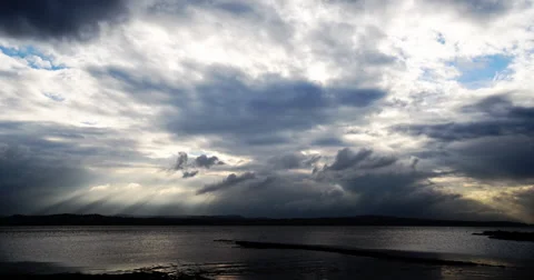 Sunbeams through moody clouds over water time-lapse 動画素材 68719583