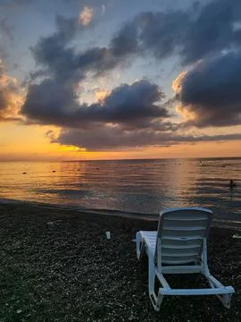 Sunbed on empty pebble beach on sunrise.  Relax travel concept. Stock Photos