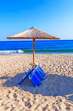 Sunbed, straw umbrella on beach background Stock Photos