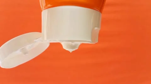 Sunblock Cream Texture Squeezed From Tube on Orange Background, Skincare Protect Stock Footage 327900019