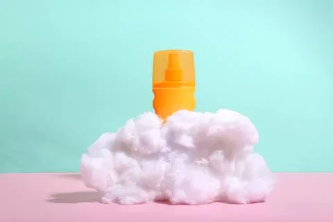 Sunblock spray bottle on fluffy cloud with pastel background 스톡 사진