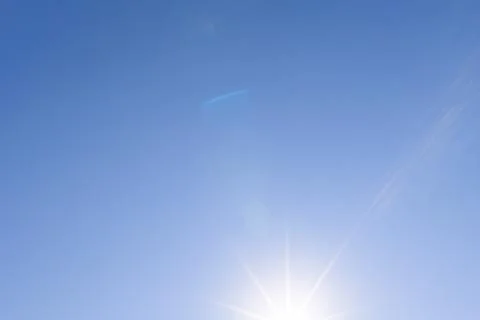 Sunburst against a cloudless blue sky with colorful optical lens flare Stock-Fotos