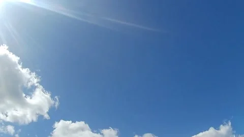 Sunburst and clouds on bright blue sky motion loop slow motion Stock Footage 333104874