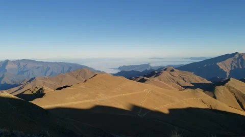 Sundown on mountain road far below and clouds in valley in background Stock Footage 156217113