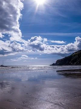 Sunflare Beach and cloud reflections Stock Photos