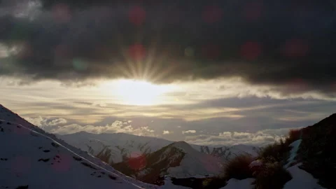 Sunflare down lens with snow clad mountains clouds and golden light Stock Footage 159693358