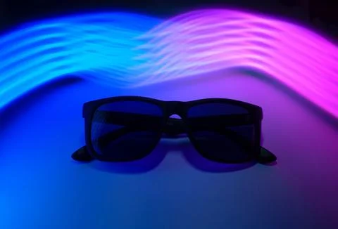 Sunglasses on a background of multicolored neon rays Stock Photos