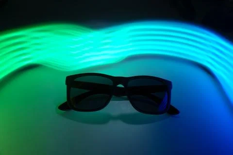 Sunglasses on a background of multicolored neon rays Stock Photos