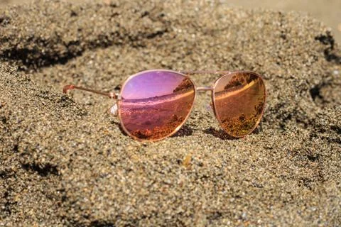 Sunglasses at the beach with sea reflection. Stock Photos