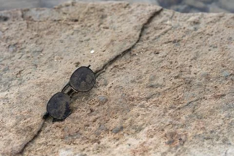 Sunglasses covered with algae and washed up on coastal rocks during a storm Stock Photos