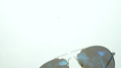 Sunglasses falling in water on white background, Stock Footage 256144384