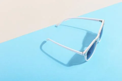 Sunglasses lie on a colored background casting a harsh shadow, concept art of Stock Photos
