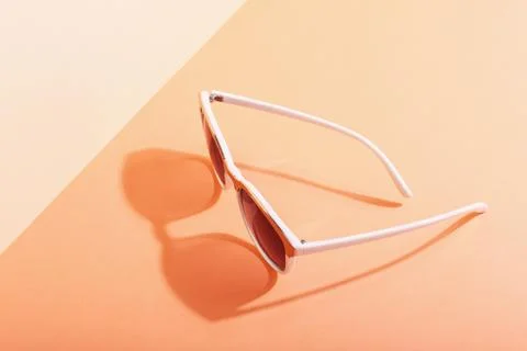 Sunglasses lie on a colored background casting a harsh shadow, concept art of Stock Photos