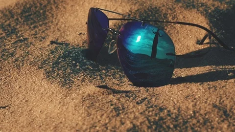 Sunglasses lying on the beach and reflecting girl silhouette Vídeo Stock 109505557