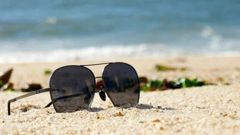 Sunglasses lying on the beach in summer as waves break on the shore Stock Footage 108642435