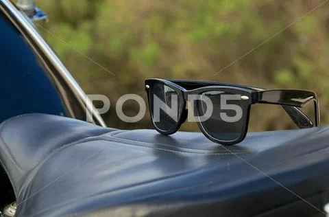 Sunglasses on motorcycle saddle Stock Photos