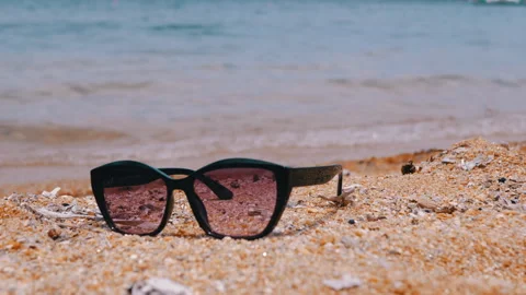 Sunglasses resting on the sandy beach while enjoying a beautiful sea view in the Stock Footage 312015191