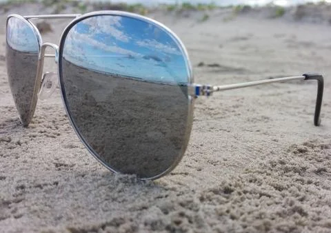 Sunglasses on sand with beach reflection Stock Photos