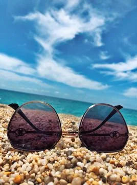 Sunglasses on the sand sea. A long awaited vacation at sea. Stock Photos