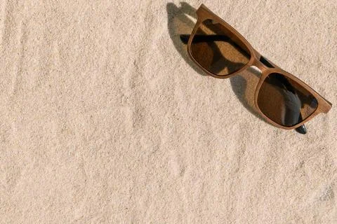 Sunglasses on sandy beach surface with soft shadows Stock Photos