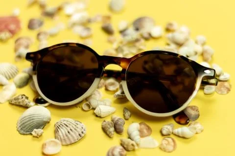 Sunglasses, shells and pebbles closeup on white background Stock Photos