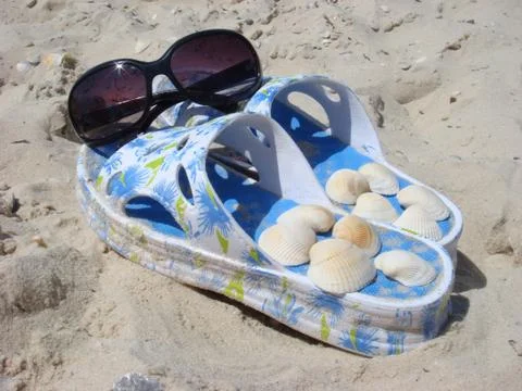 Sunglasses on slippers with shellfish at a beach Stock Photos