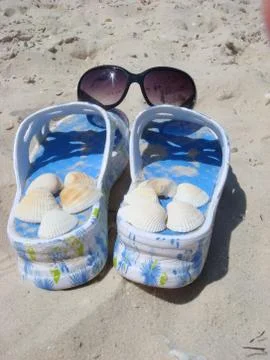 Sunglasses on slippers with shellfish at a beach Stockfoto's