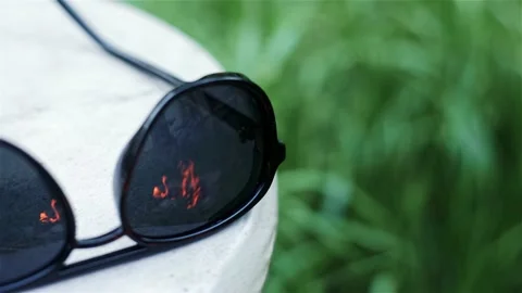 Sunglasses in which burning fire and bicycle are reflected against. Stock Footage 210238386