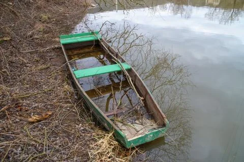 Sunken river boat with reflection of tree branches Stock Photos