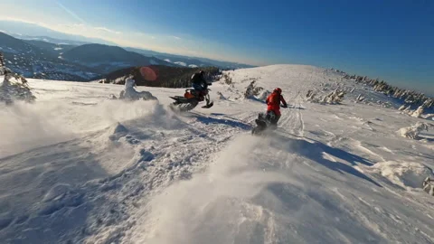 A sunlight aerial top view in mountains, two guy on snowmobile jumps and rides Stock Footage 189406065