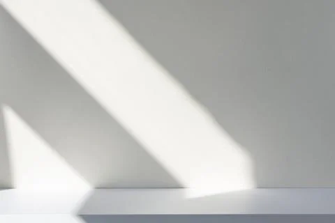Sunlight and abstract shadows on the wall and white desk. Stock Photos