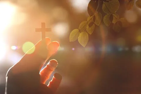 Sunlight and the cross of Jesus Christ held in the hand, Christian background Stock Photos