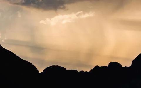 Sunlight and falling rain over silhouetted range Stock Photos