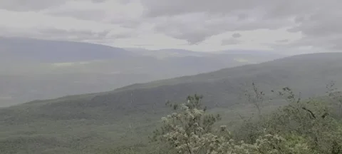 Sunlight and rain over lush green valley landscape Stock Footage 329072497
