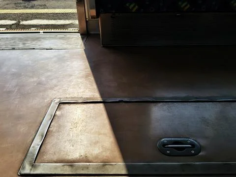Sunlight and shadow on an empty commuter train floor with open doors. Stock-Fotos