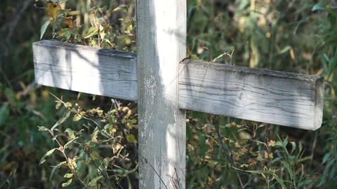 Sunlight and shadows dance on an old wooden grave marker cross Stock Footage 139973472